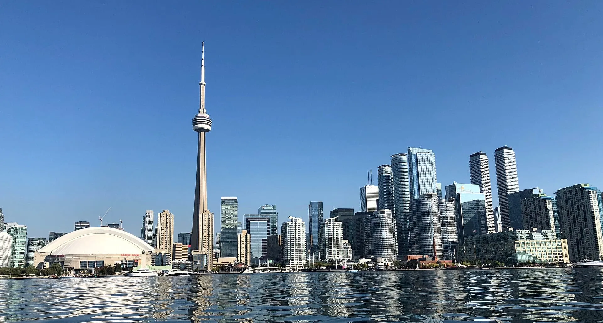 The CN Tower and downtown Toronto towers seen across the harbour from the water on a clear morning.